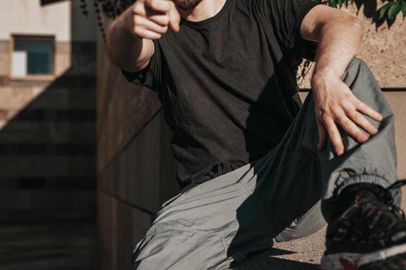 Das Bild zeigt den Künstler Jens Kuhlmann in einer urbanen, modernen Umgebung abgebildet. Mit ernstem Blick und stilvoller Kleidung posiert er vor einer industriellen Kulisse.