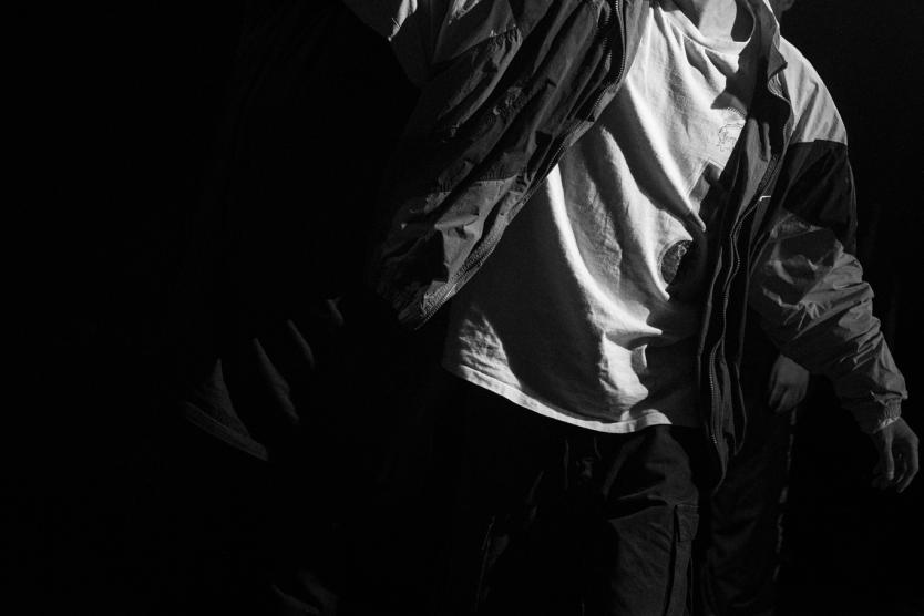 Das Bild zeigt den Künstler Nam Nguyen The in Schwarz-Weiß, dynamisch nach vorne schreitend mit ausgestrecktem Arm, was seine Bewegung kraftvoll betont.