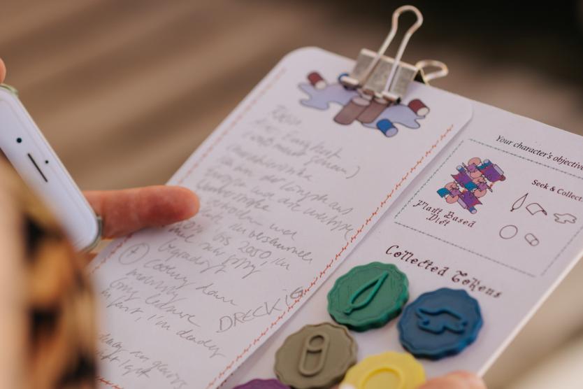 Das Bild Zeit eine Person die die ein Notizbogen in der Hand hält mit bunten Spielsteinen.