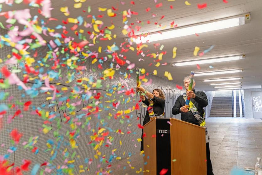 Zwei Personen feiern im Tunnel mit Konfettikanonen – festlicher Abschluss einer Performance.