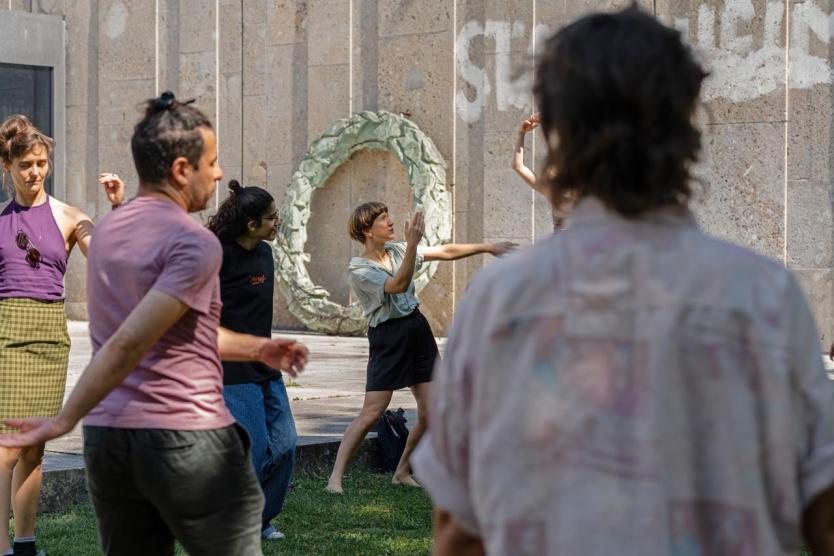 Mehrere Personen stehen in einem Kreis und machen auflockernde Bewegung und atmen dazu.